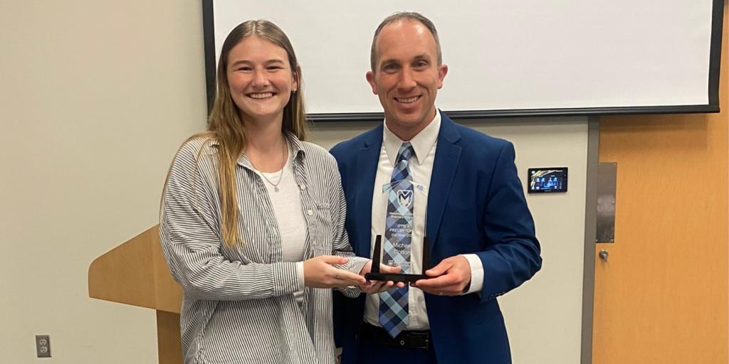 Manchester University student presenting an award to Dr. Michael Cotton.