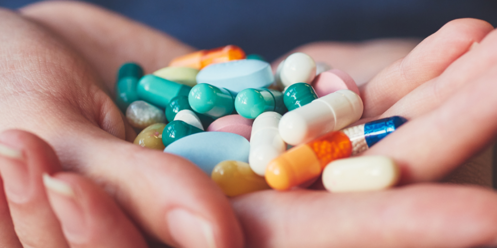 hands with various medications, pills, capsules