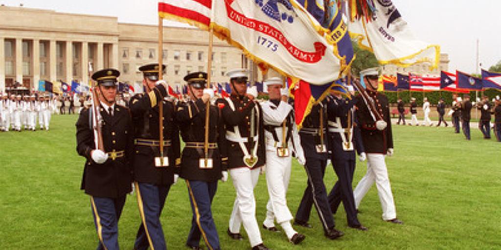 A military color guard carrying the US military flags marches in front of the Pentagon in Washington D.C.