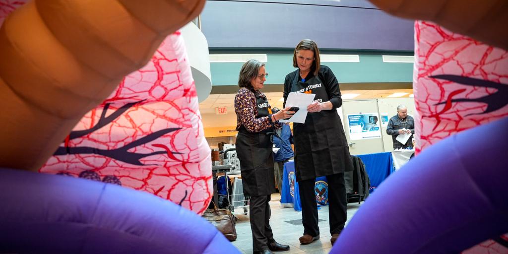 VA Staff reads a document in front of a inflatable lung during the resource fair at the medical center