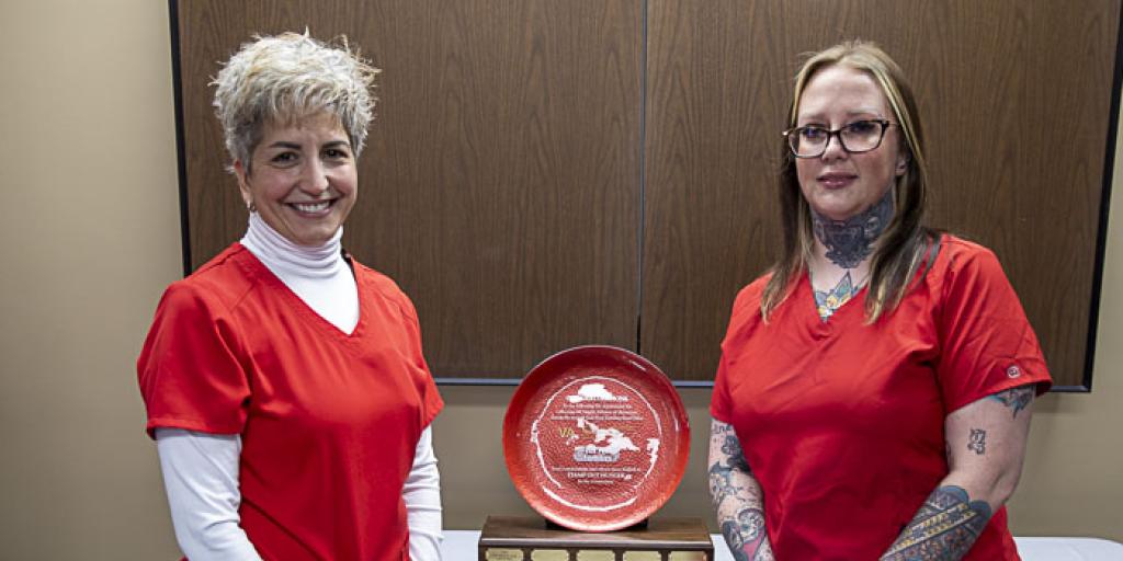 Two nurses from Kerrville VA Medical Center stand tall next to trophy after winning the fight against hunger.