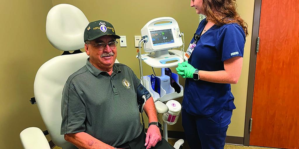 Photograph of a Veteran in a clinical setting, being seen by an LVN.