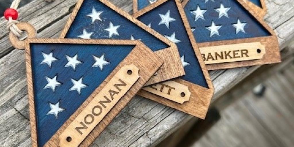 Handmade wooden ornaments  in triangular shape of folded American flag with name. 