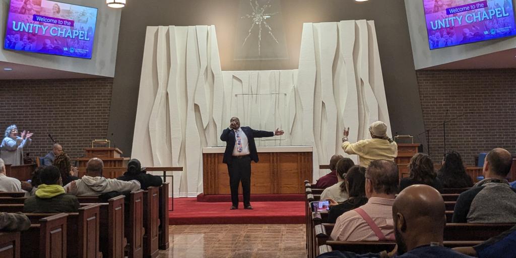 Singer performing with arms outstretched in front of audience.