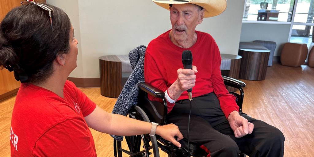 Volunteer Britney Kalina encourages WW II U.S. Army Veteran James Studderville in a karaoke song at West Texas VA Health Care System community center.