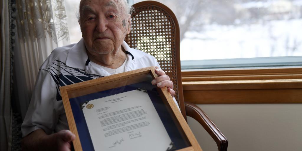 Mr. Raymond Hanley holds a certificate from Denis McDonough, Secretary of Veterans Affairs, extending heartfelt wishes for a happy 100th birthday.