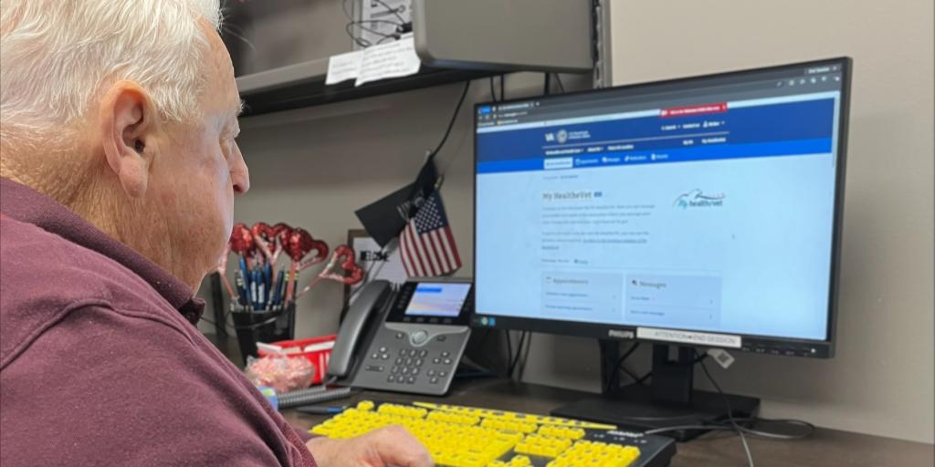 An older man focused on typing at a computer keyboard