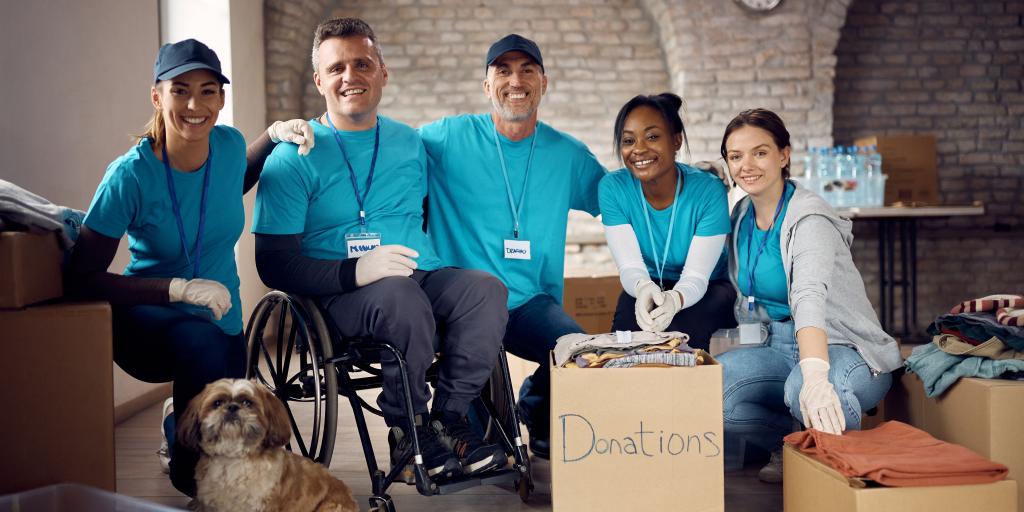 Team of happy diverse volunteers and dog at humanitarian aid center.