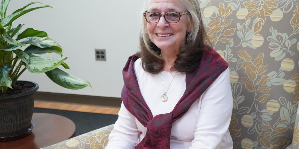 Volunteer Brenda Novak sitting in an armchair and smiling at the camera