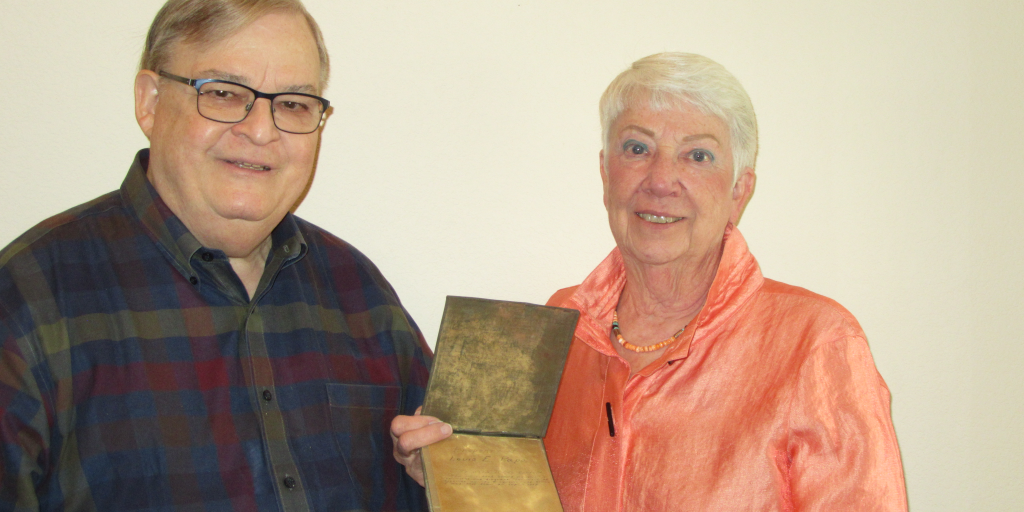 David and Cheryl Denslow hold her father's WWII POW diary written on toilet paper.