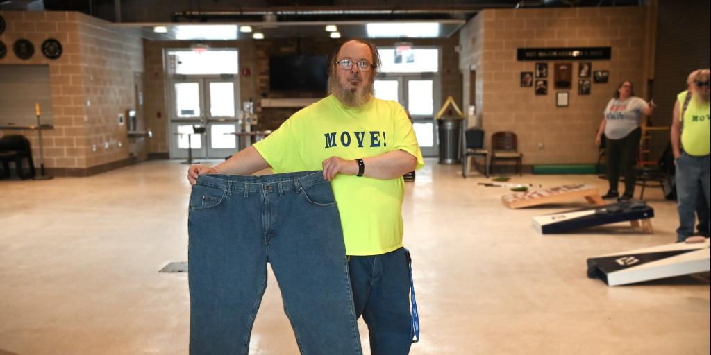 A man holding up a large pair of blue jeans.