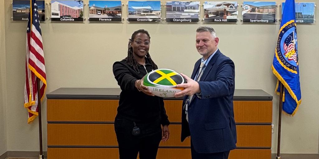 Donneisha Smith (left) and David "Brett" Vess pose for a photo holding a rugby ball.