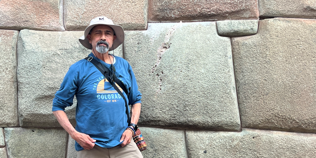 Air Force Veteran Ed Lucero stands in front of a stone wall while visiting Cusco, Peru, after completing chronic pain therapy at VA Eastern Colorado.