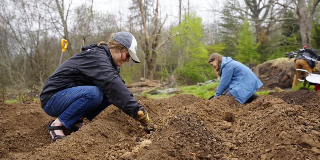 Two women are digging in the earth at the Veterans Healing Farm in Mills River, NC.
