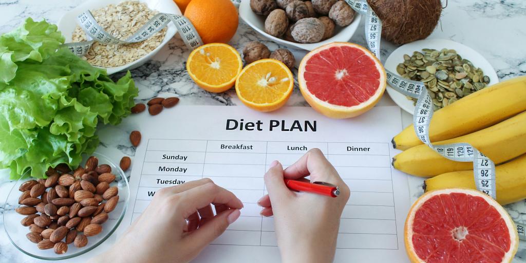 Photo showing fruits, vegetables and a person filling out a diet plan.