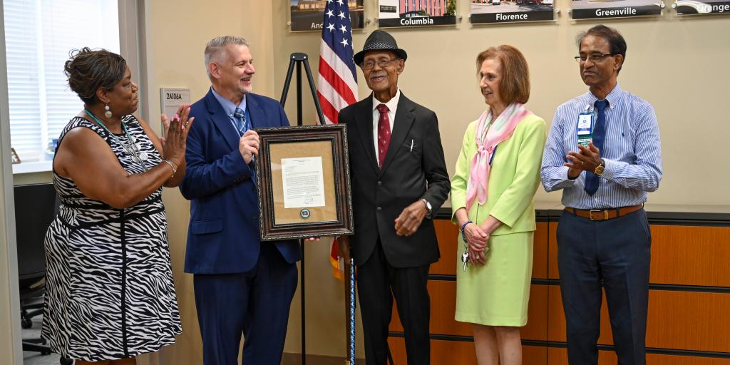 Columbia VAHCS Acting Executive Director/CEO David Brett Vess presents Navy Veteran & Centenarian, Lee O. McKinnon, a letter & Centenarian coin.