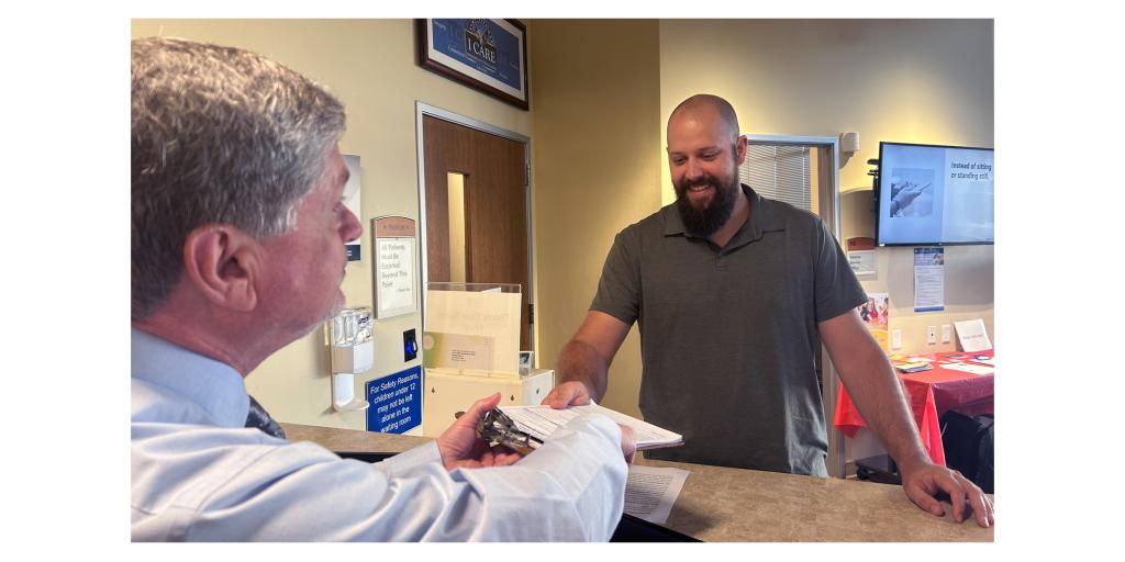 Thaddeus Rix, a Marine Corps Veteran, receives check-in paperwork from Scott Tribolet, lead Medical Support Assistant, during a VA appointment.