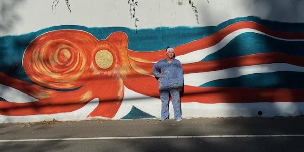 VA Nurse foregrounded against her reddish-brown octopus mural which she still works to complete on a daily basis.