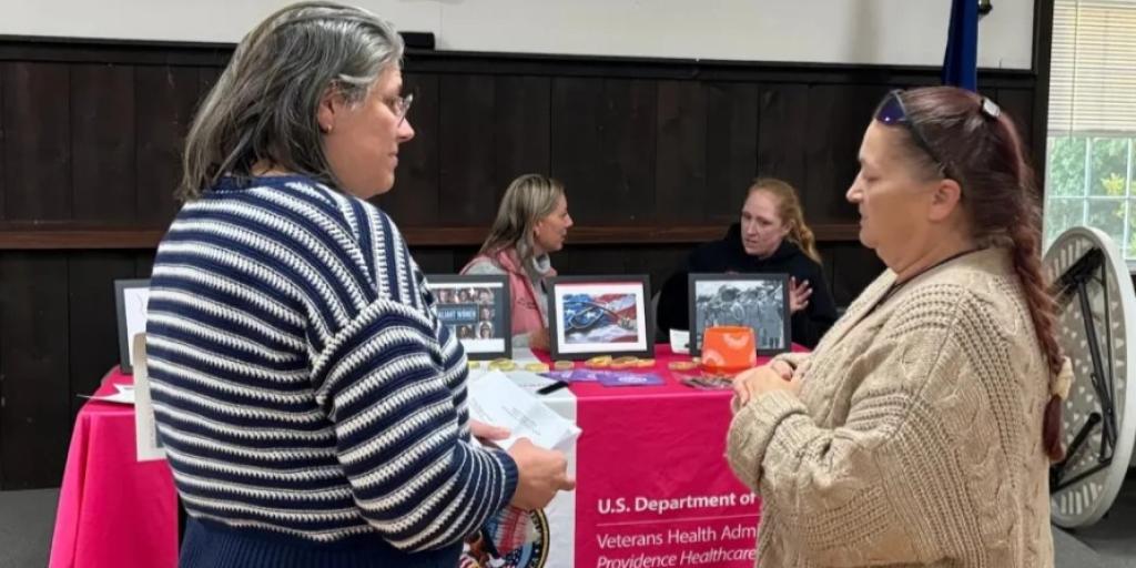 VA Providence's Joanne Barrett speaks to a fellow Veteran at her table while Women Veterans converse during the event.