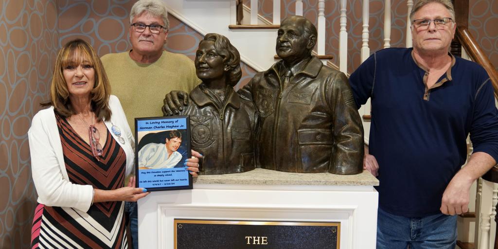 Norman Mayhew's siblings present a plaque in his honor next to the statue of the founders of the Fisher House