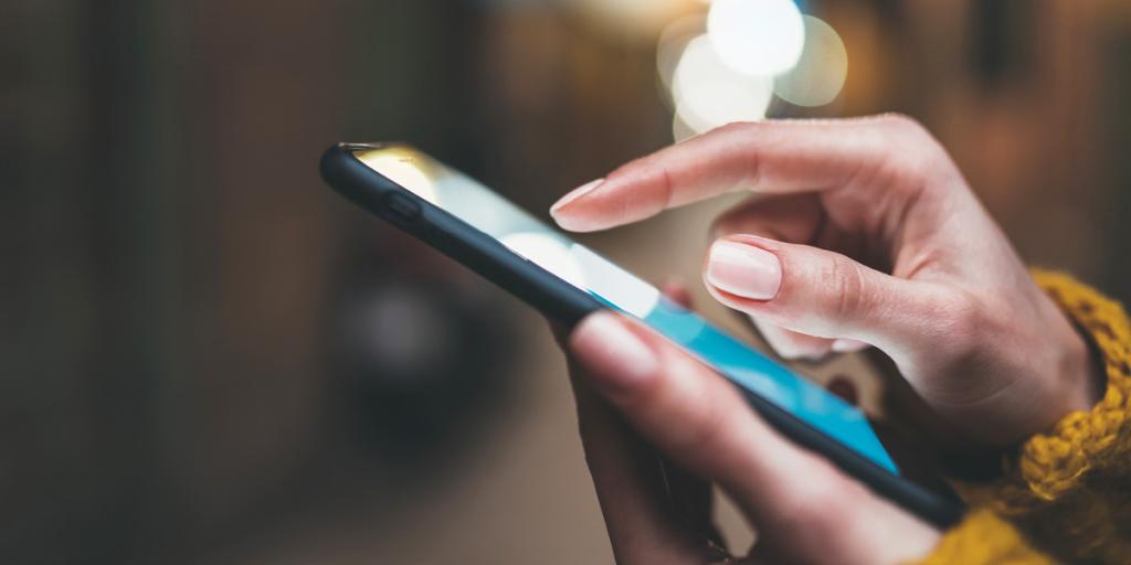 Female hands holding a mobile phone as if they are texting someone.