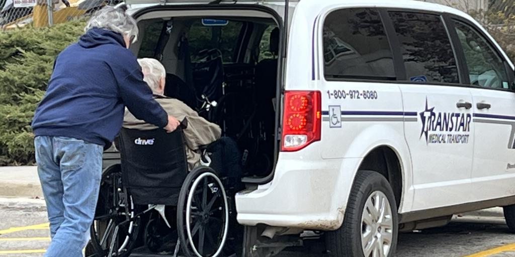Man pushes a man in a wheelchair into a van