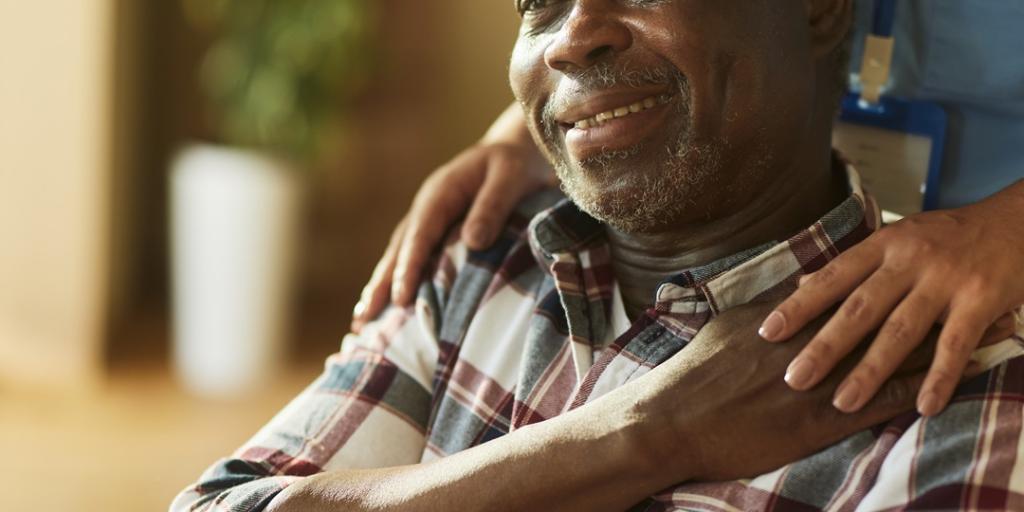 Veteran in a wheelchair smiling while receiving caregiver support.