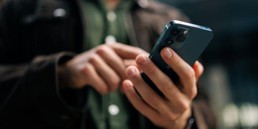 A man holding a cell phone and text messaging with VA's appointment system.