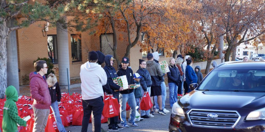 People stand by hundereds of meal kits in red bags, prepared to hand out at the Ken Garff Automotive Drive Out Hunger event