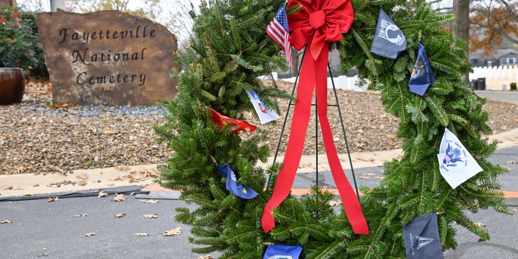 stone in the background with name of  cemetary and holiday wreath with all branches of service in the fore ground
