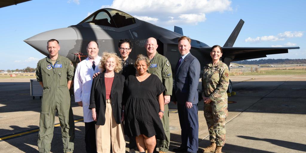 group of VA employees and military standing in front of a fighter plane