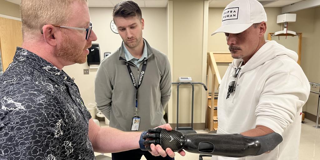 Man with prosthetic hand shakes hands with another man.