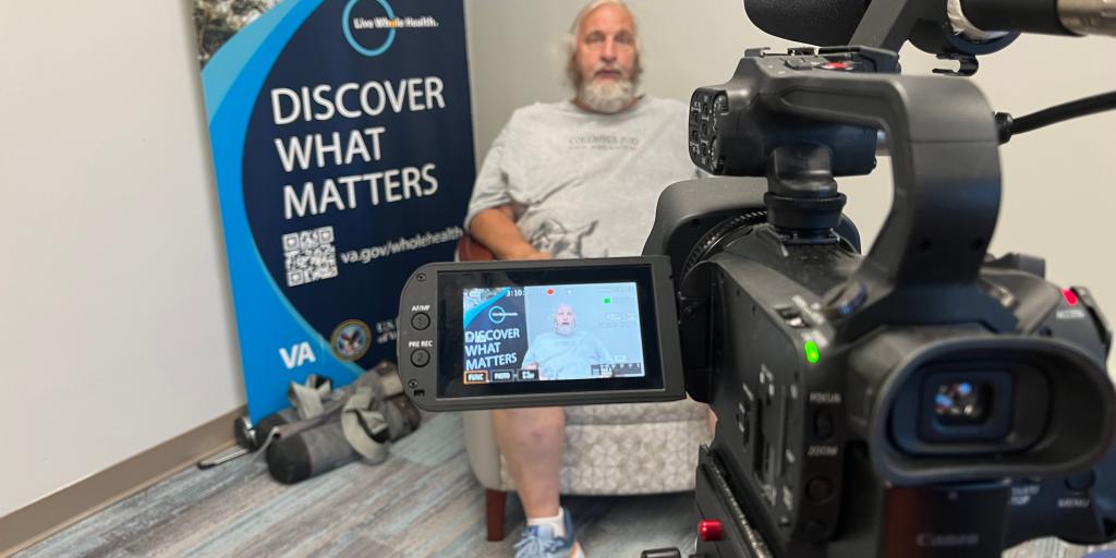 Veteran Charles Barlow in front of a Whole Health banner.