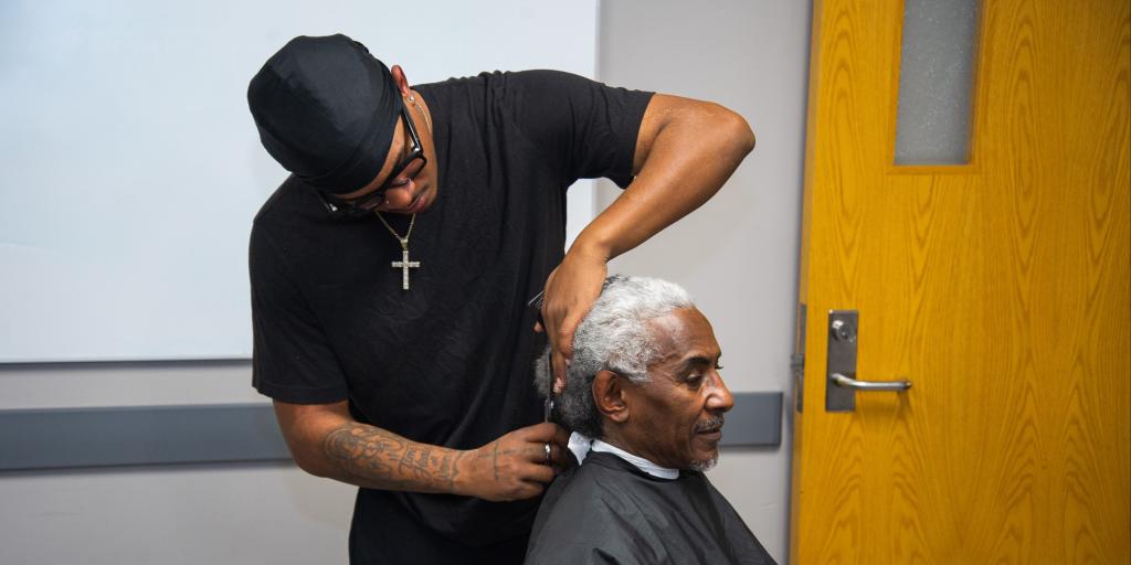 student barber cuts hair of Veteran