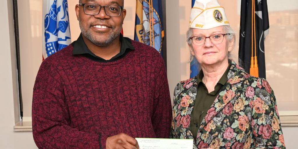 Birmingham VA Executive Director and DAV holding the donation check, smiling.