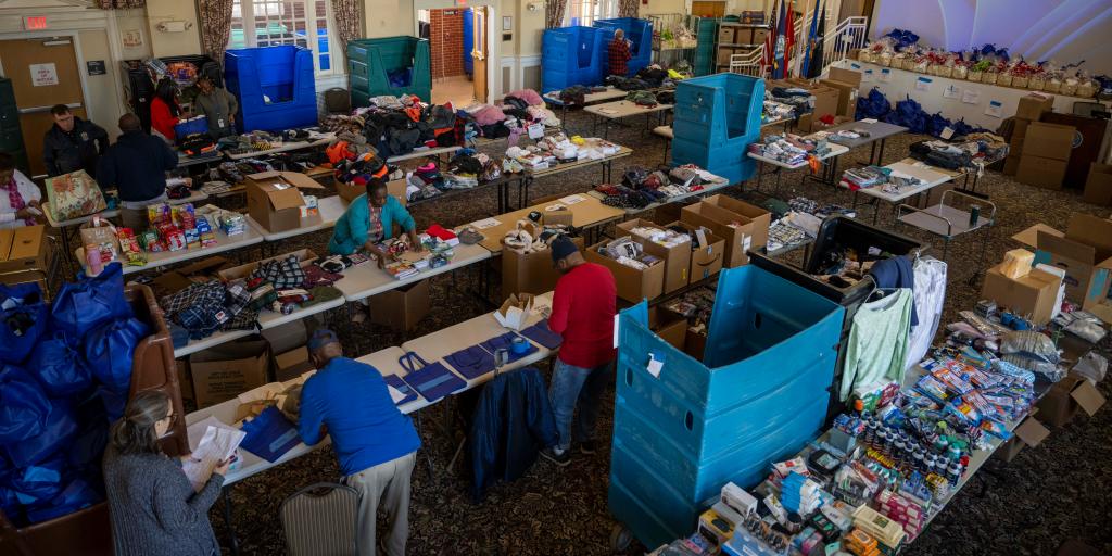 A large room filled with tables and boxes, people sorting items.