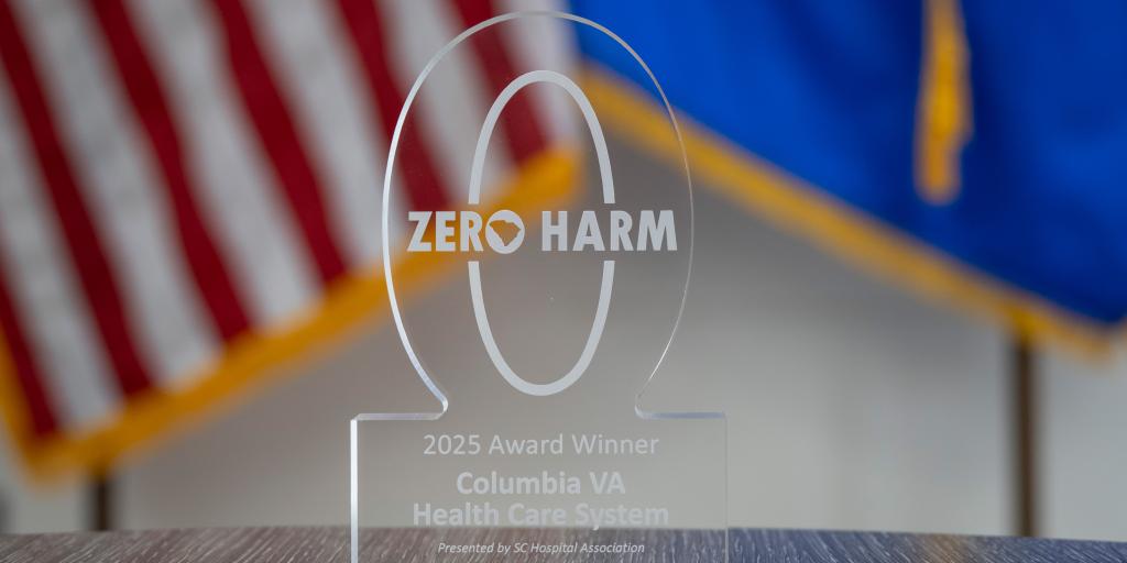 Clear glass Zero Harm award with American and agency flags in the background.