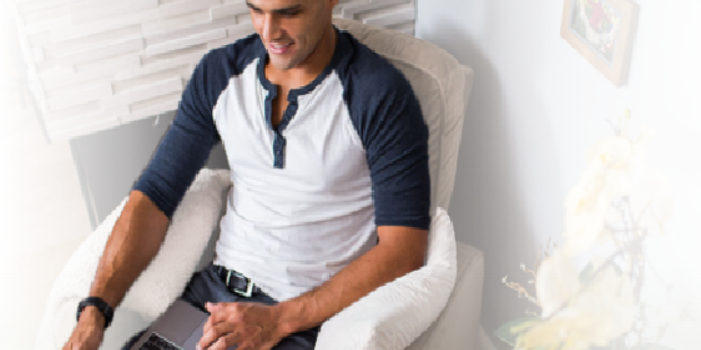 Man in a blue and white shirt using a laptop.