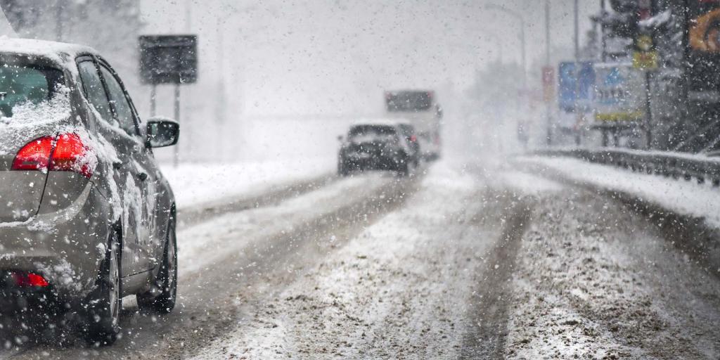 Cars and a bus driving on a snowy road.