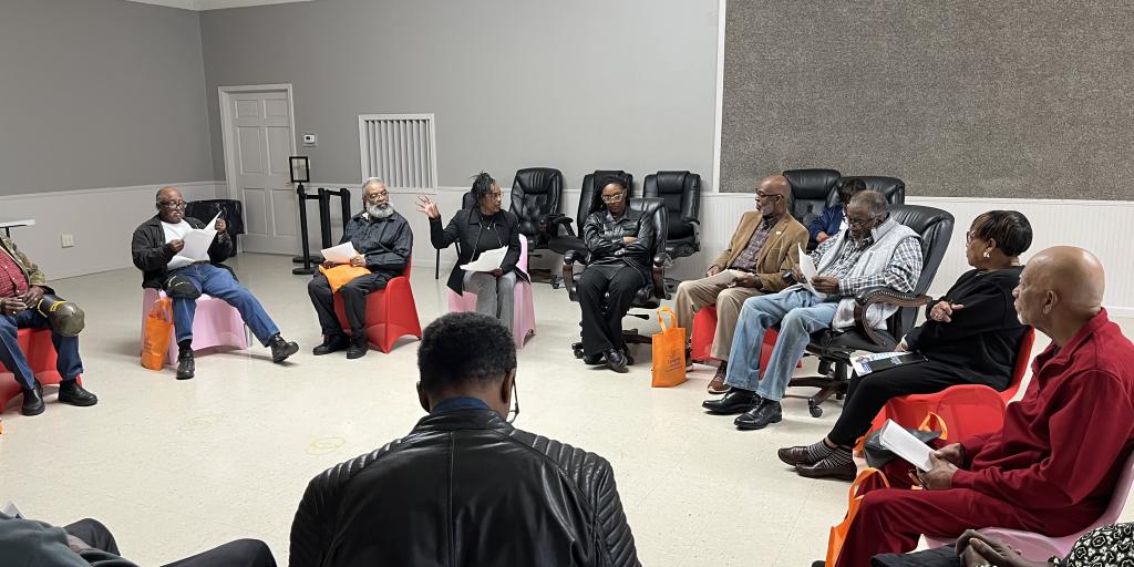 Group of people in a circle discussing in a room.