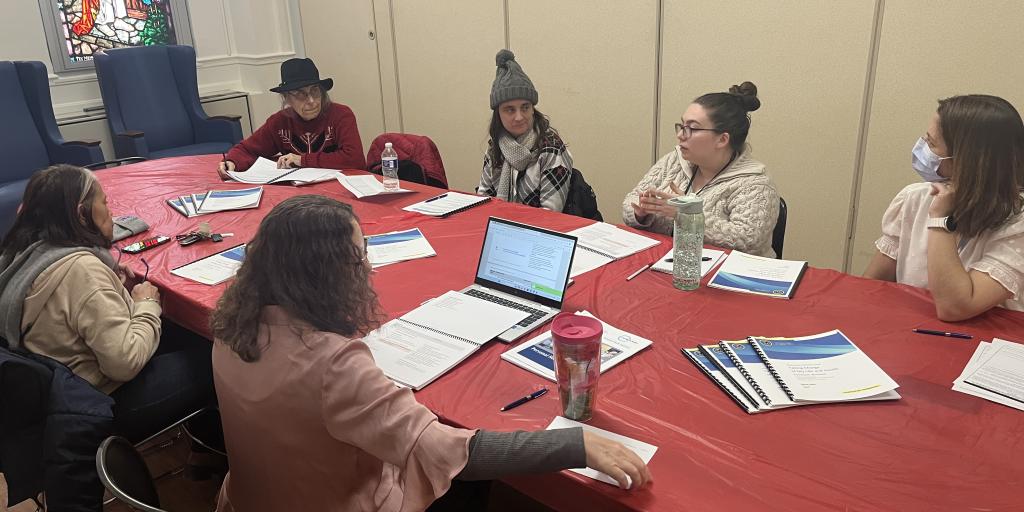 Group of people in a meeting with laptops and papers.