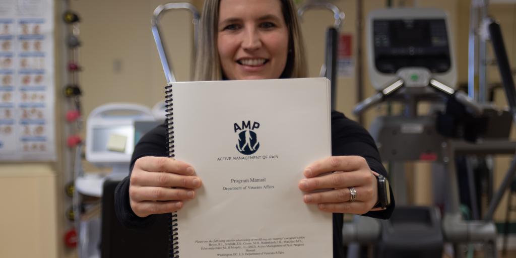 Woman in a hospital room holding a spiral bound booklet.