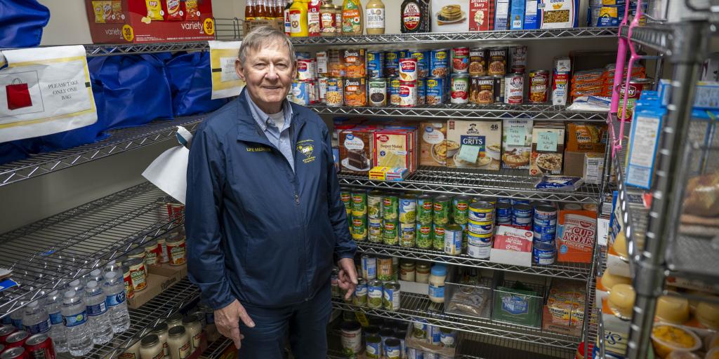 Man smiling in front of shelves full of food.