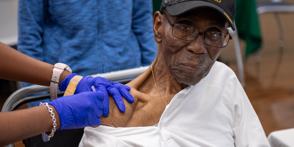 Veteran receives vaccine from healthcare worker in a clinic.