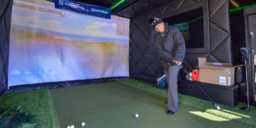 Navy Veteran Traci Williams practices her swing at golf simulation event. 
