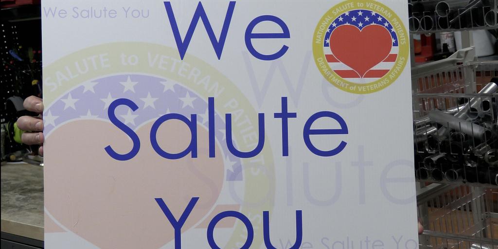 Sign reads "We Salute You" with American flag and heart.