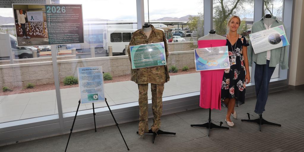 Woman in black dress standing next to mannequins in military uniform and pink dress.