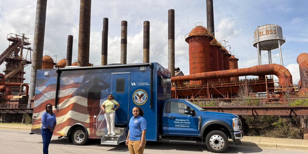 Two women in front of a blue truck, one woman on the truck.