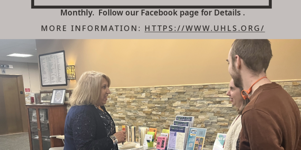 People discussing Upper Hudson Library System visits at a table in Albany, VA.