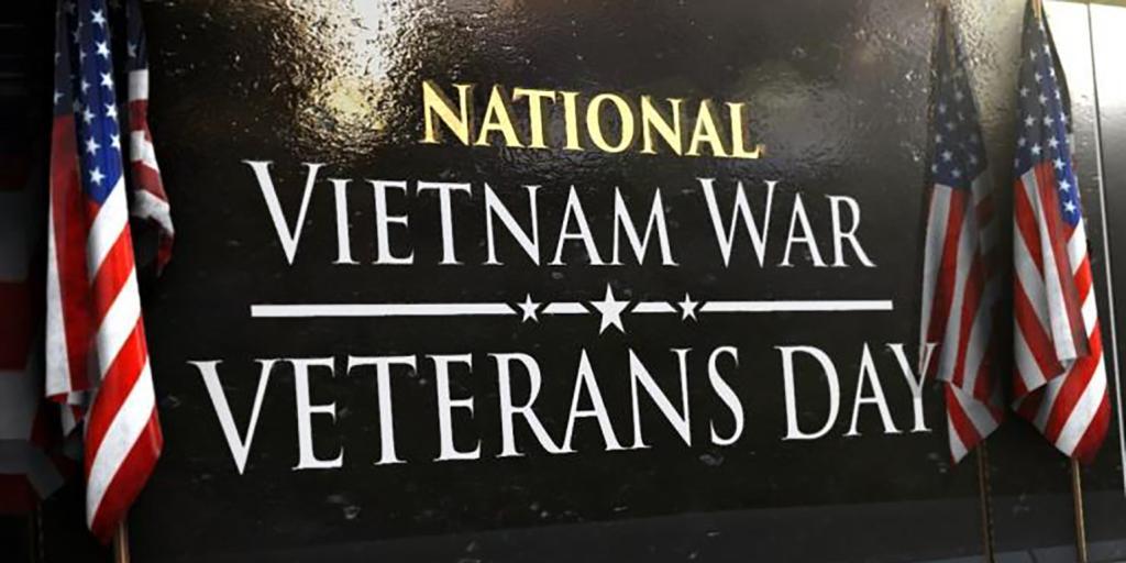 Sign reading "National Vietnam War Veterans Day" with two American flags.